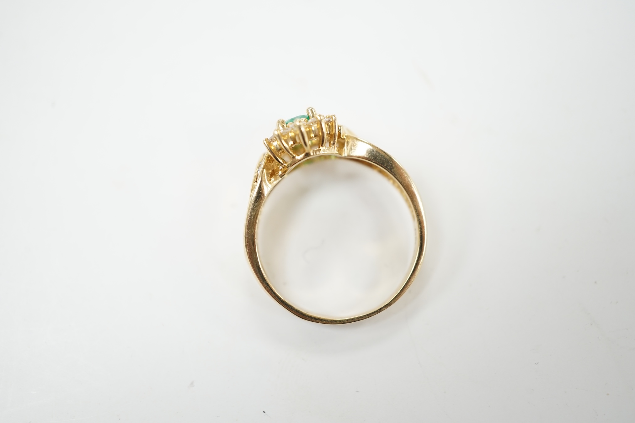 A modern 14k, emerald and diamond cluster set ring, with baguette cut diamond set shoulders, size Q, gross weight 4.9 grams. Condition - fair